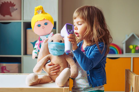 child pretending to be doctor taking temperature of doll doll